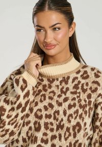 Maglione leopardato beige e marrone con colletto a coste color sabbia. Texture morbida, vestibilità ampia e maniche lunghe con un design rilassato.