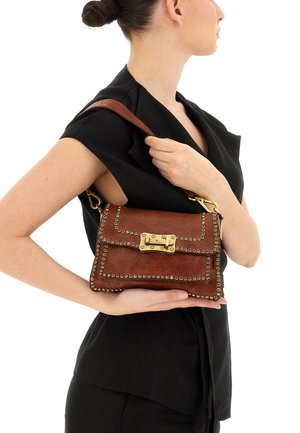 Borsa a mano in pelle marrone con ferramenta color oro, dettagli borchiati lungo i bordi e chiusura a pattina. Tracolla regolabile.