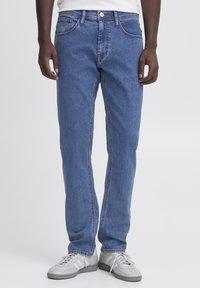 Jeans in denim blu con gamba dritta, cinque tasche e chiusura a bottone argentato; presenta sbiadimenti leggeri e cuciture a contrasto.