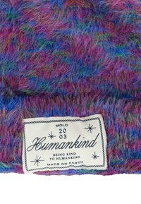 Kleurrijke, zachte stof met paarse, blauwe en groene tinten. Bevat een wit label met zwarte tekst die "Humankind" en sterren leest.