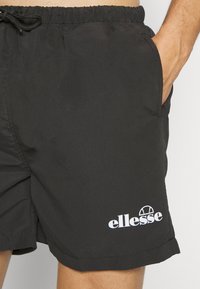 Fekete úszósort elasztikus derékkal és húzózsinórral, oldalsó zsebekkel, valamint fehér "ellesse" logóval a bal alsó lábszáron.