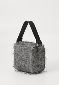 Sac à motif chevrons noir et blanc avec des franges texturées, doté d'une bandoulière noire solide et de quincaillerie en argent. Forme rectangulaire.