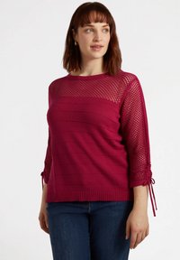 Fuchsian stickad tröja med meshdetaljer på ärmarna, med horisontella ränder, ribbat fåll och justerbara knytband på ärmarna.