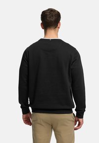 Sudadera negra con mangas largas y cuello redondo, con bajo y puños acanalados. Fabricada con tela suave, diseño minimalista sin logotipos.
