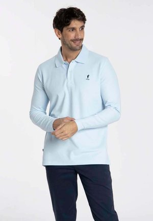 Polo-shirt à manches longues bleu clair en coton avec col, comportant un logo brodé sur la poitrine gauche et un ourlet droit.
