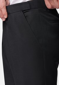 Czarne spodnie wykonane z gładkiego materiału, z dopasowanym krojem, bocznymi kieszeniami i eleganckim fasonem z czystym pasem.