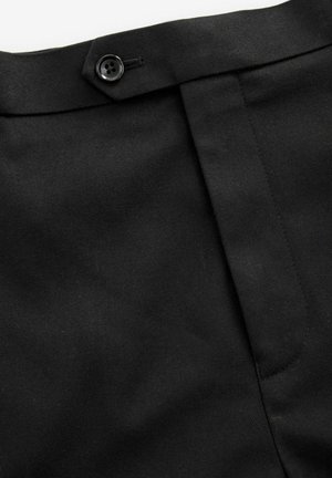 Pantalones negros ajustados con un frente plano, cierre de botón y tejido texturizado. Presenta una cinturilla suave y costuras laterales discretas.