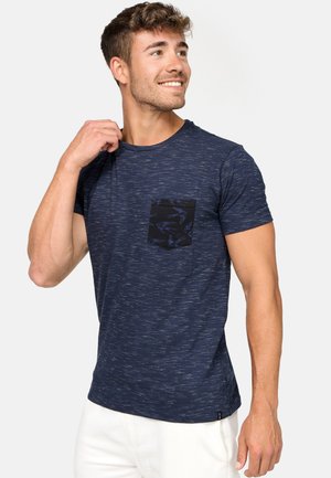 T-shirt en coton bleu marine avec un design texturé, des manches courtes et une poche noire avec un motif d'oiseau. Finition en tissu lisse.