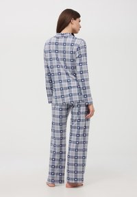 Set da pigiama a quadri blu navy e grigi, con top con bottoni e pantaloni larghi, entrambi decorati con piccoli motivi a cuore rosa. Tessuto morbido.