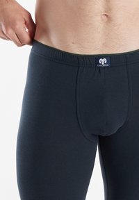 Slipping in cotone elasticizzato blu navy con una vestibilità aderente, dotati di una vita elastica verde e una etichetta con logo al centro anteriore.