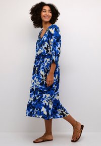 Blå blomster midi kjole med V-hals, trekvartærmer og lagdelt nederdel. Lavet af letvægtsstof med en blanding af hvide og marineblå detaljer.