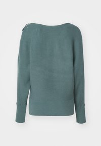 Sinen ribbattu neule, jossa on venepääntie, pitkät hihat ja vetoketjuvaste vasemmalla olkapäällä. Pehmeä rakenne ja tiukasti istuva helma.