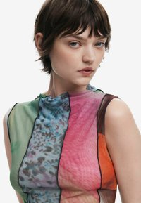 Multicolored sleeveless top in sheer fabric; features green, pink, blue, and orange panels with black trim and varied textures.