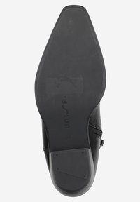 Semelle d'une chaussure en cuir noir avec une forme pointue, un talon en caoutchouc texturé et un logo embossé. Présente une finition lisse et une flexibilité modérée.