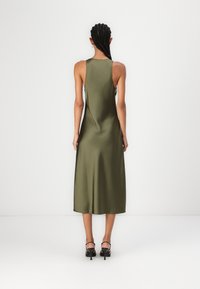 Rochie midi din satin verde măsliniu cu un spate înalt, textură netedă și design minimalist. Are bretele subțiri și o margine ușor fluturată.