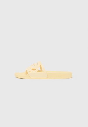 Yellow rubber slide sandal with cut-out geometric design on the strap, flat sole, and embossed logo detail on the side.