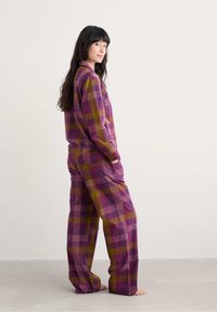 Paarse en pruimen geruite pyjama set van zachte stof, met een ontspannen pasvorm, zijzakken en lange mouwen.