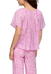 Roze blouse met bloemenpatroon en korte mouwen, met een geplooide halslijn. De lichte stof zorgt voor een vloeiende silhoutte.