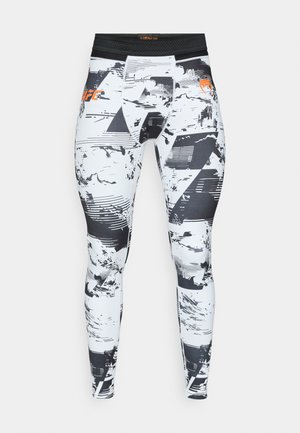 Κολάν συμπίεσης σε λευκό χρώμα με μαύρα και γκρι γεωμετρικά σχέδια. Διαθέτει μαύρη μέση, ελαφρύ ύφασμα και λεία υφή.