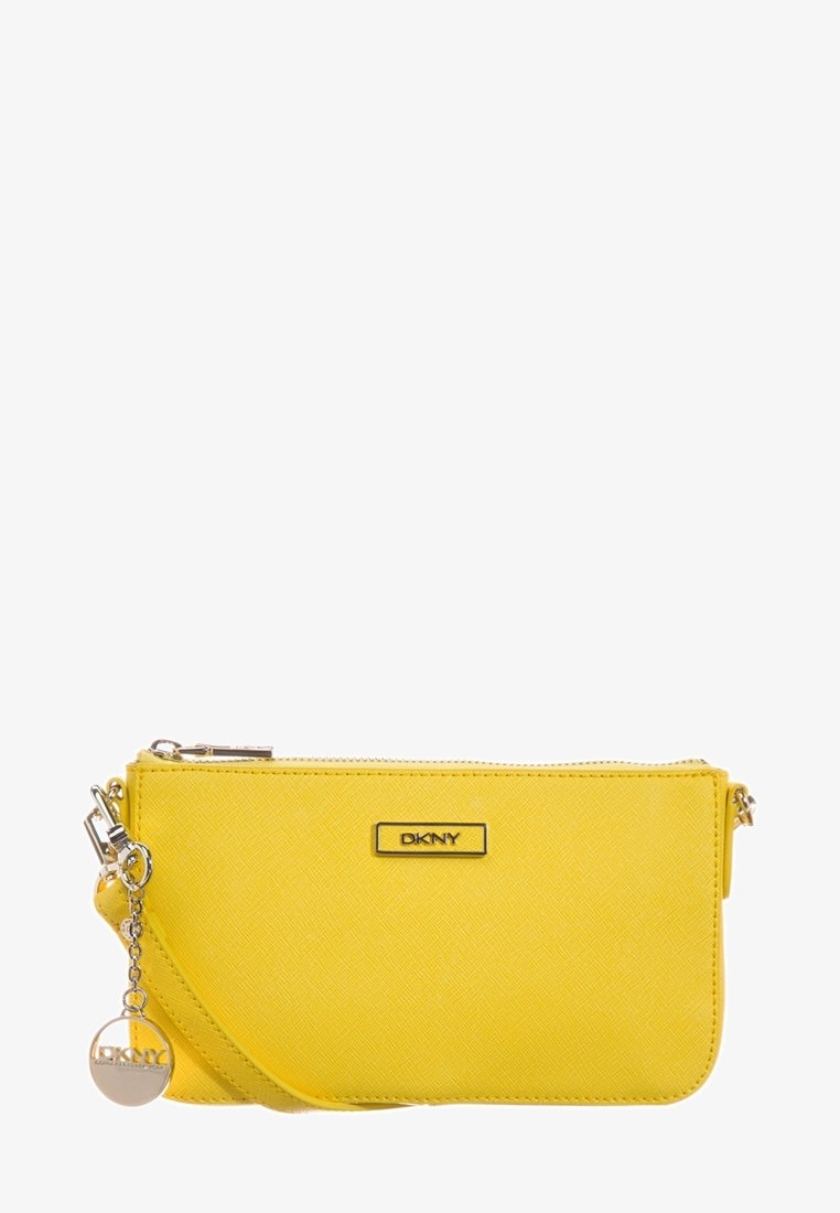 Pochette DKNY jaune vif avec surface texturée, fermeture éclair argentée et breloque ronde en argent avec le logo DKNY sur fond blanc.