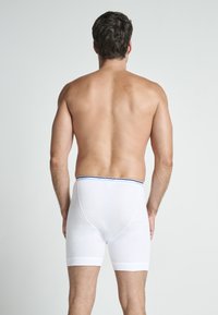 Boxer shorts de algodón blanco con una banda de acento en azul marino en la cintura. La tela parece suave con un ajuste ceñido, mostrando un diseño de pierna de longitud media.