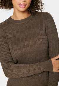 Pull en maille côtelée marron avec un col rond et des manches longues, présentant un tissu texturé qui offre une apparence et un ajustement confortables.