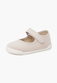 Chaussure Mary Jane en toile beige avec une bride Velcro, bout rond, semelle en caoutchouc blanc et tige texturée.