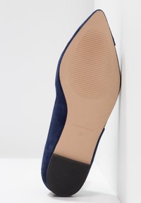 Granatowe zamszowe buty na szpilce z gładką podeszwą, posiadają jasnobrązową wkładkę i czarny gumowy obcas. Rozmiar 37, wyprodukowane w Hiszpanii.