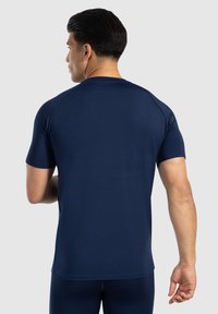Granatowa koszulka sportowa z krótkim rękawem, gładka w dotyku i dopasowana, z rękawami raglanowymi oraz okrągłym dekoltem.