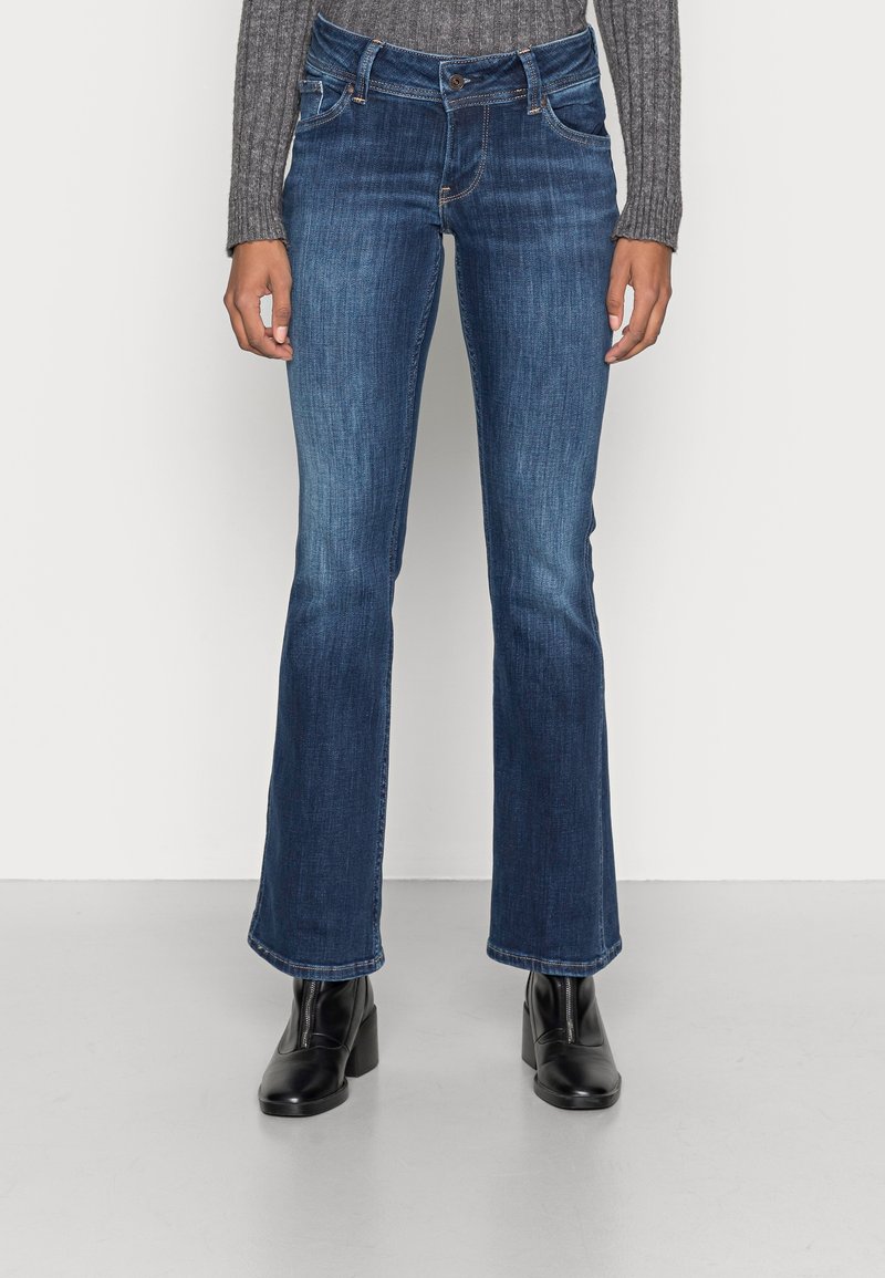 Flares i jeans i mörkblått med medelhög midja, fem fickor och subtila sömnadsdetaljer. I kombination med svarta klackstövlar.