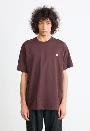 T-shirt en coton marron avec une coupe décontractée, un col rond et des manches courtes, présentant un petit logo blanc sur la poitrine gauche.