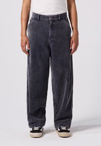 Grå kordfløjspants med en afslappet pasform, der har høj talje, frontlommer og strukturerede lodrette striber, sat sammen med sorte sneakers.