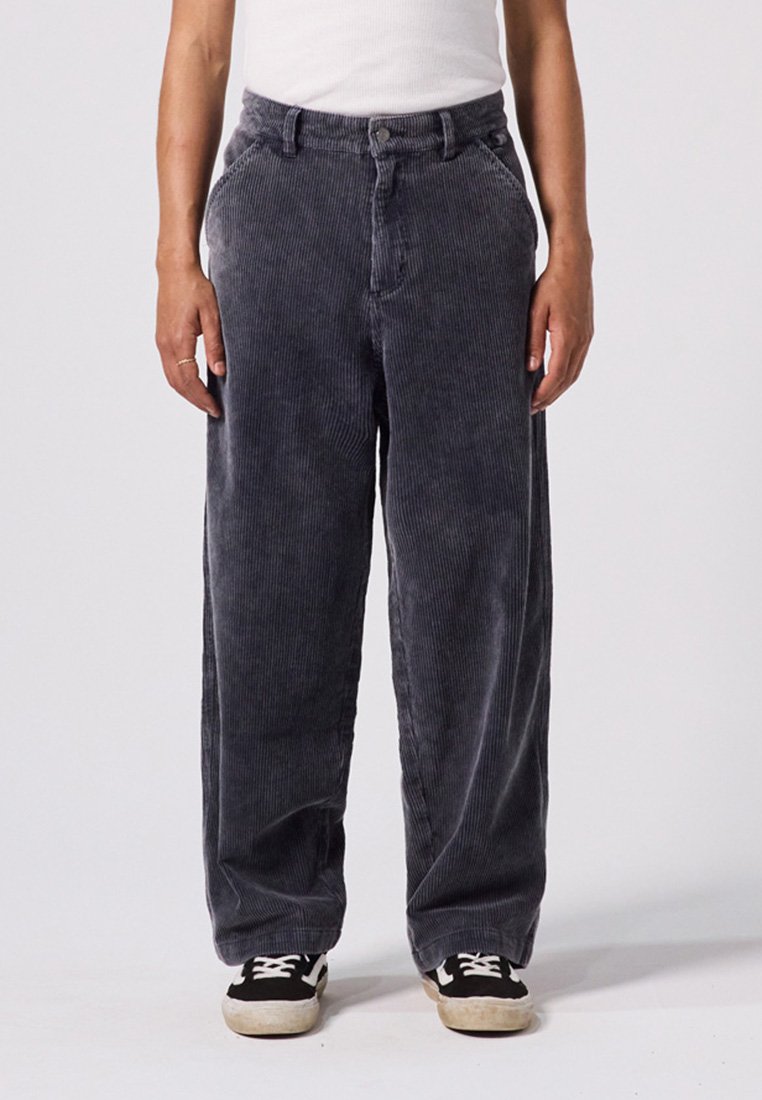 Grå kordfløjspants med en afslappet pasform, der har høj talje, frontlommer og strukturerede lodrette striber, sat sammen med sorte sneakers.