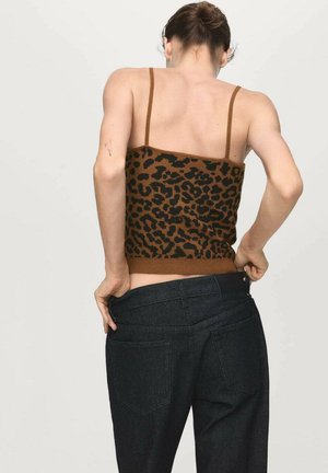 Hnedé tričko s leopardím vzorom z pleteniny s tenkými ramienkami, nosené s tmavými džínsami. Pozornosť sa sústreďuje na textúru trička a vzor látky.