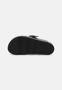 Gray felt slipper with a black rubber sole, adjustable strap, and a textured footbed for comfort. Notable rounded toe and minimal design.