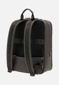 Zaino nero con schienale in rete strutturata, spallacci imbottiti e sottili dettagli con logo; presenta un design elegante e moderno e una forma strutturata.