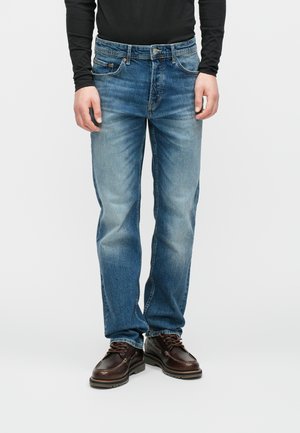 Denim jeans i mellemblå med en falmet struktur, lige snit, fem lommer og knaplukning, parret med brune snørebåndssko.