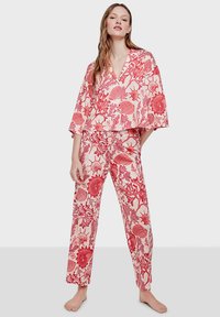 Ensemble de pyjama léger à motif floral rouge, comprenant un col en V, des manches larges et un pantalon droit à coupe décontractée sur fond uni.