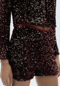 Short sequined set featuring a maroon and black color scheme, with a fitted long-sleeve top and shorts, embellished throughout with shiny sequins.
