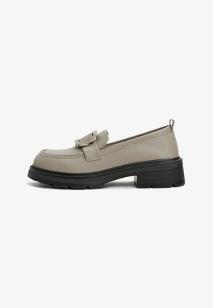 Mocassins en cuir beige avec accent de nœud, bout rond et semelle plateforme noire texturée. Comprend une languette à l'arrière.