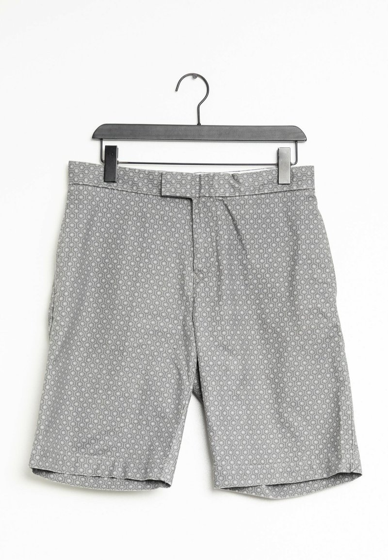Shorts gris à motifs suspendus sur un cintre en plastique noir sur fond blanc.