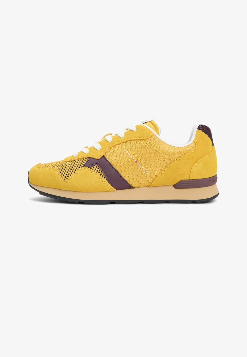 Baskets jaune et marron avec lacets blancs, textures en mesh et en suède, avec le logo Tommy Hilfiger sur le côté.