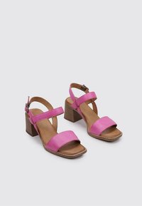 Sandales à talons en cuir rose avec deux larges brides, design à bout ouvert et talon en bois. Texture lisse et détails de couture minimaux.
