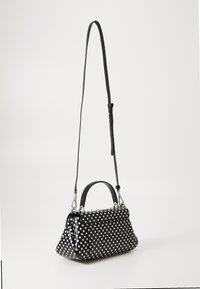 Sort håndtaske med polka-prikker lavet af blødt glossy materiale, med en top håndtag og et langt justerbart rem. Sølv hardware detaljer er synlige.