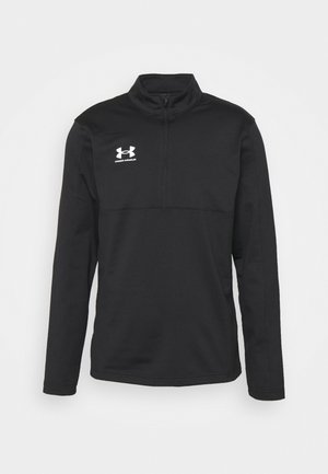 Svart långärmad Under Armour tröja med kort dragkedja och vitt logo på vänster bröst mot en vit bakgrund.