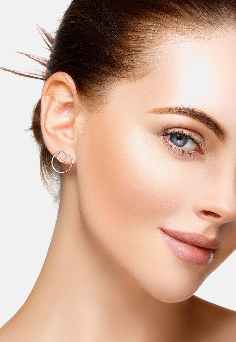 Silverfärgade cirkulära örhängen med en dubbelringdesign, som visar en polerad yta. Bakgrunden är enkel för att sätta fokus på smyckena.