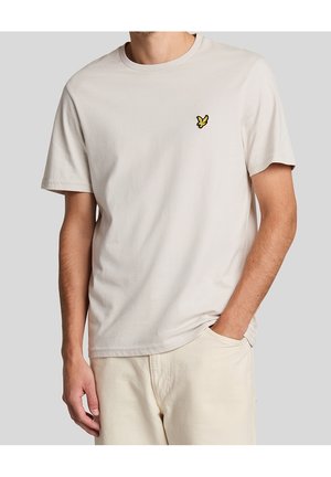 Jasno beżowa koszulka wykonana z bawełny, z okrągłym dekoltem i małym żółtym haftowanym motylem na lewej piersi. Krótkie rękawy.