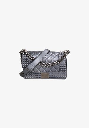 Sac à main en cuir gris matelassé avec des accents cloutés, une bandoulière en chaîne et une plaque de marque. Présente une forme rectangulaire et une surface texturée.