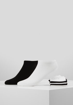 Schwarz-weiße Knöchelsocken. Die schwarze Socke hat eine glatte Textur; die weiße Socke hat gerippte Akzente. Drei weitere gestreifte Socken sind daneben gestapelt.