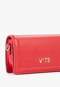 Clutch in pelle rossa con logo dorato "V°73". Presenta un design piatto e angoli arrotondati. Include un attacco in metallo dorato per le cinghie.